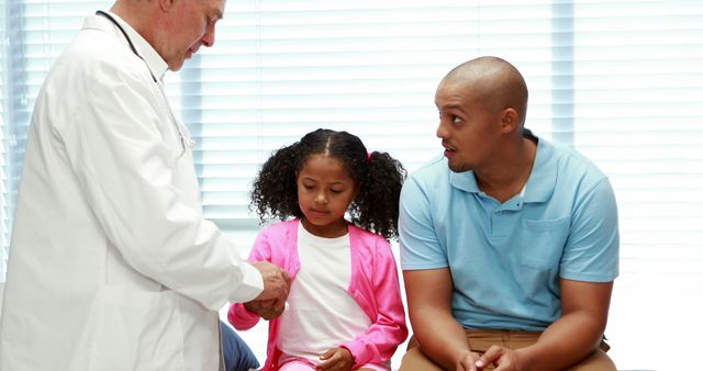 Pediatrician examining young girl with concerned father - Download Free Stock Images Pikwizard.com