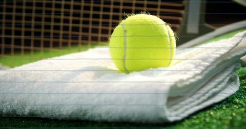 Tennis Ball on Folded Towel Next to Tennis Net