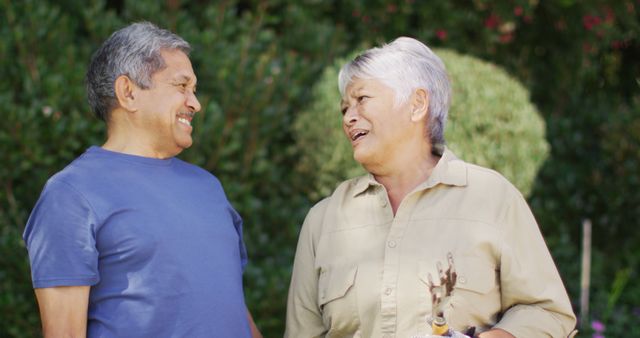 Image of happy biracial senior couple laughing and talking in garden. active retirement lifestyle, senior relationship and spending time together.