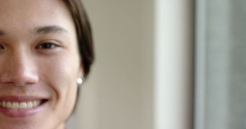 Half-face portrait of smiling asian man with earring