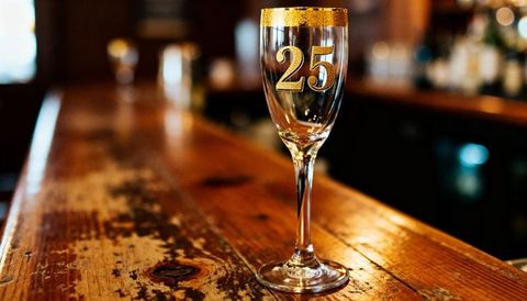 Gold 25 Champagne Flute on Rustic Wooden Bar for 25th Anniversary Celebration