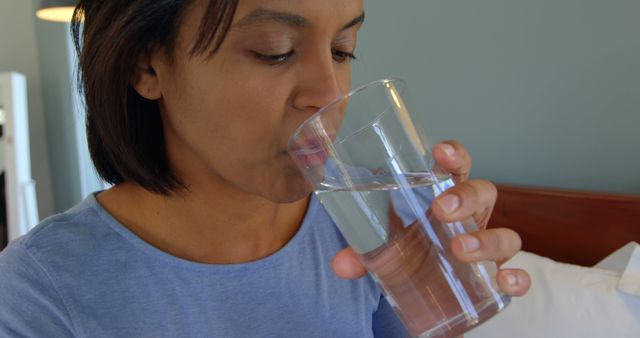 An African American woman is drinking a glass of water, with copy space. Staying hydrated is essential for maintaining good health and well-being.