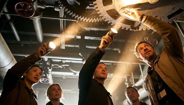 Technicians Inspecting Large Rusted Gear in Industrial Engine Room with Flashlights