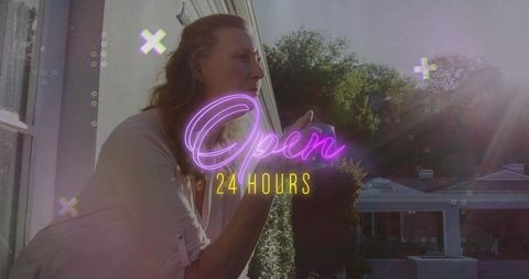Leaning woman cupping hand at window toward rooftop garden with neon open 24 hours sign