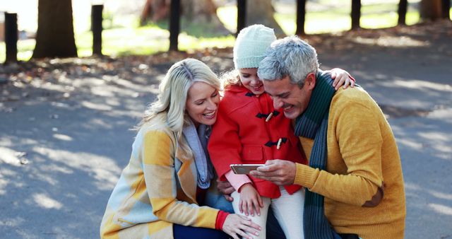 Happy Family in Autumn Park Sharing Fun Moments with Smartphone - Download Free Stock Images Pikwizard.com