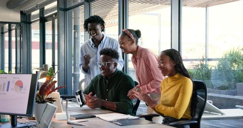 People Collaborating Cheerfully in Bright Offices Analyzing Data on Screen