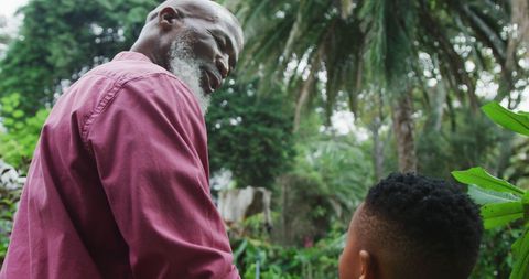 Grandfather and Grandson Walking in Lush Garden Outdoors