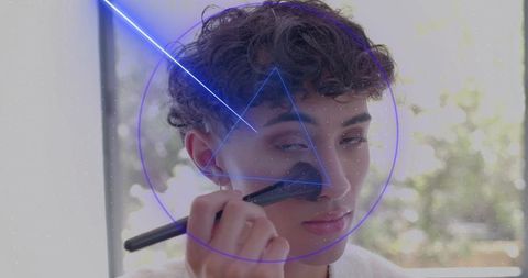 Young man applying makeup with brush by window neon blue geometric overlay beauty portrait