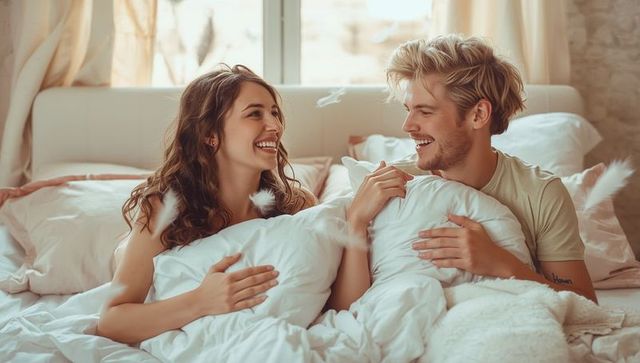 Playful couple enjoying pillow fight in cozy bedroom