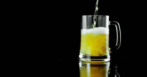 Cold Refreshing Beer Mug with Foam on Black Background