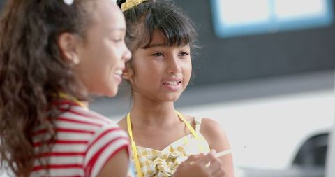 Biracial Girls Engaged in Classroom Discussion Holding Pencil