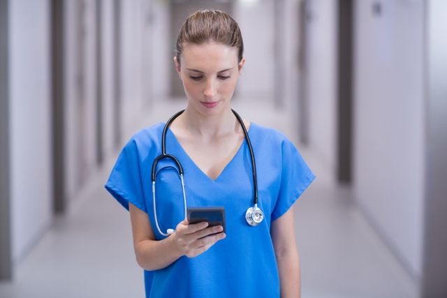 Female doctor using mobile phone in corridor of hospital