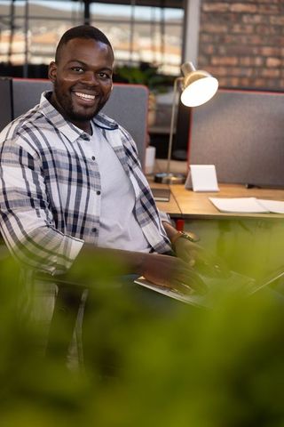 Businessman Smiling While Working on Laptop in Modern Office Environment