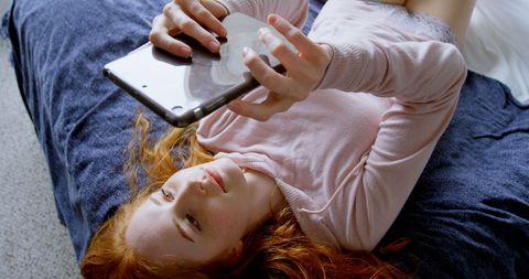 Young Woman Relaxing on Bed with Smartphone