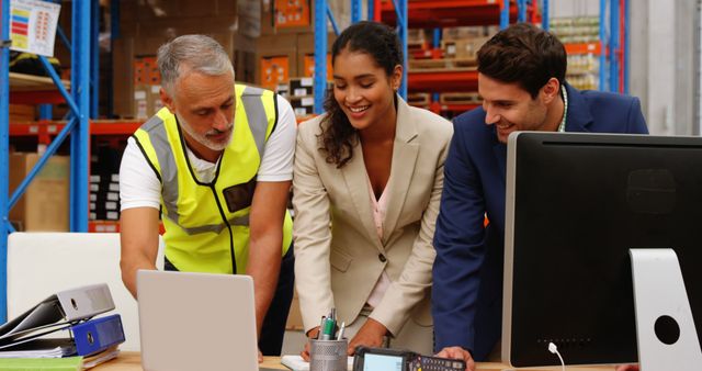 Happy diverse female and male colleagues using computer and laptop at desk in storage warehouse - Download Free Stock Photos Pikwizard.com