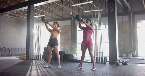 Fitness Women Performing Swing Exercise with Kettlebells in Modern Gym