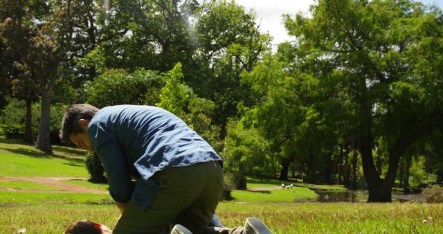 Man Providing First Aid in Park on Sunny Day - Download Free Stock Images Pikwizard.com