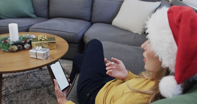 Woman in Santa Hat Relaxing Using Smartphone on Couch - Download Free Stock Images Pikwizard.com