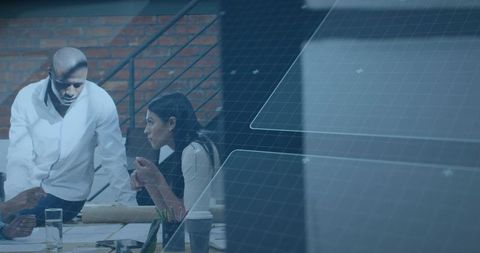 Team collaborating at table with digital grid overlay, modern office brainstorming