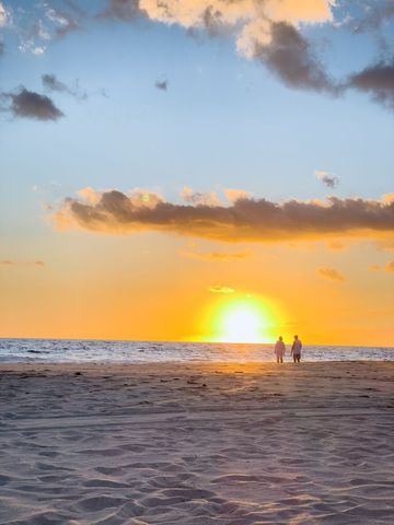 Serene Beach Sunset with Silhouetted Couple Walking Along Shoreline