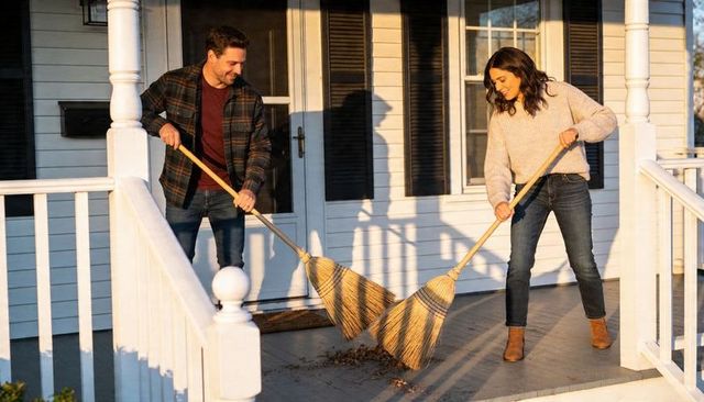 Couple sweeping front porch at golden hour using natural straw brooms for yardwork