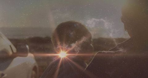 Cradling mother holding hooded baby at sunset with sun flare and starfield overlay