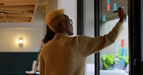 Man brainstorming on glass partition in modern office setting