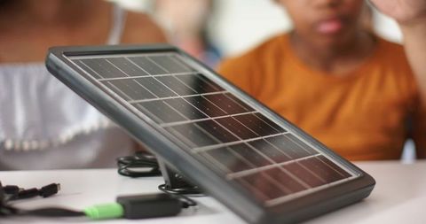 Students examining portable solar panel and testing connector in stem workshop