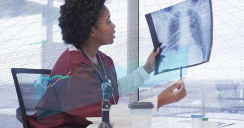 Clinician examining chest x-ray with digital analytics overlay, pointing with pen while analyzing ra