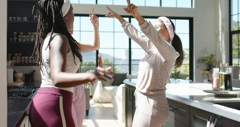 Sunlit dance: african american women dancing and laughing in modern open-plan kitchen