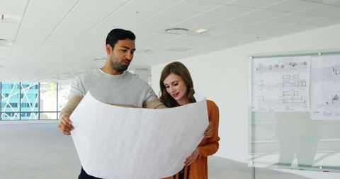 Collaborating Team Reviewing Blueprint in Modern Office