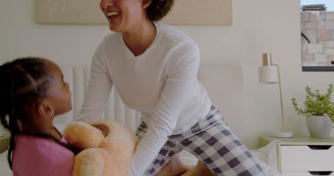 Mother and Daughter Enjoying Playtime with Teddy Bear on Bed