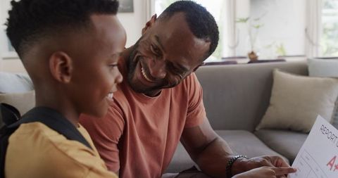 African american father celebrating son receiving a+ report card sharing proud moment