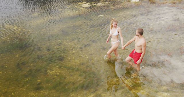 Caucasian couple walking in lake water and holding hands with copy space - Download Free Stock Photos Pikwizard.com