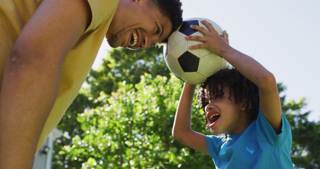 Happy biracial man and his son playing football in garden - Download Free Stock Photos Pikwizard.com
