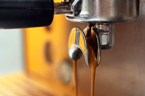 Close-up of espresso machine pouring fresh coffee into portafilter