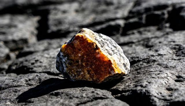 Orange mineral vein on dark basalt rock casting strong shadow and textured contrast