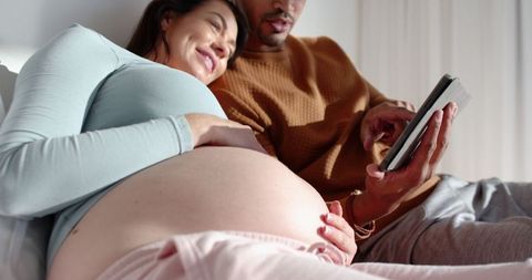Pregnant Couple Relaxing on Sofa in Cozy Living Space