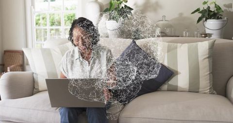 Chinese woman typing on laptop at home with AI neural network hologram overlay