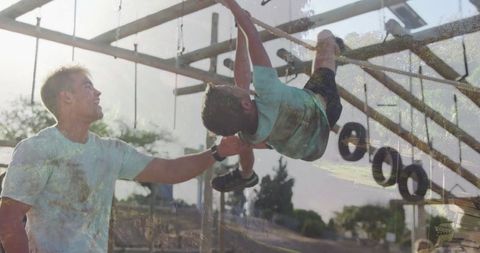 Parent supporting child on outdoor monkey bars at park