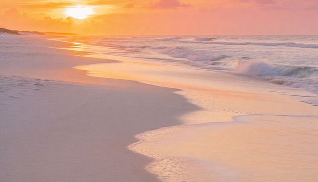 Pastel sunrise reflections on curving shoreline with gentle waves and pristine wet sand