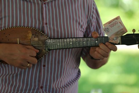 Serbian musician playing tamburica with currency note