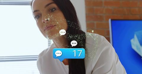 Businesswoman leaning at desk watching floating chat alert badge 17 in office near blinds