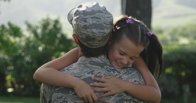 Caucasian male soldier embracing smiling daughter in garden, copy space. Soldier, armed forces, home coming, patriotism and defence concept, unaltered.