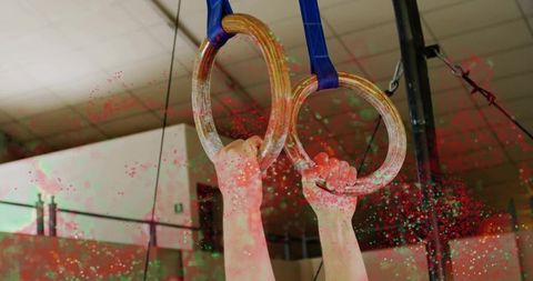 Gripping wooden gymnastic rings pulling on blue straps chalked hands showing strength and focus