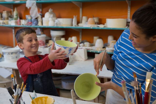 Female potter and boy painting bowl in pottery workshop