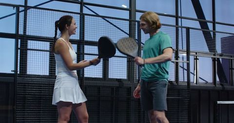 Healthy Duo Engaging in Paddle Sport on Modern Court