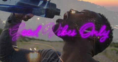 Dusk hydrating athlete drinking from blue sports bottle with neon good vibes only