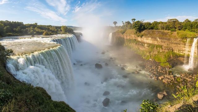Cascading waterfall pouring into rugged gorge with mist plume, river boulders, lush cliffside