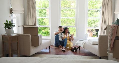 Happy Couple Unpacking Boxes in New Home with Laptop